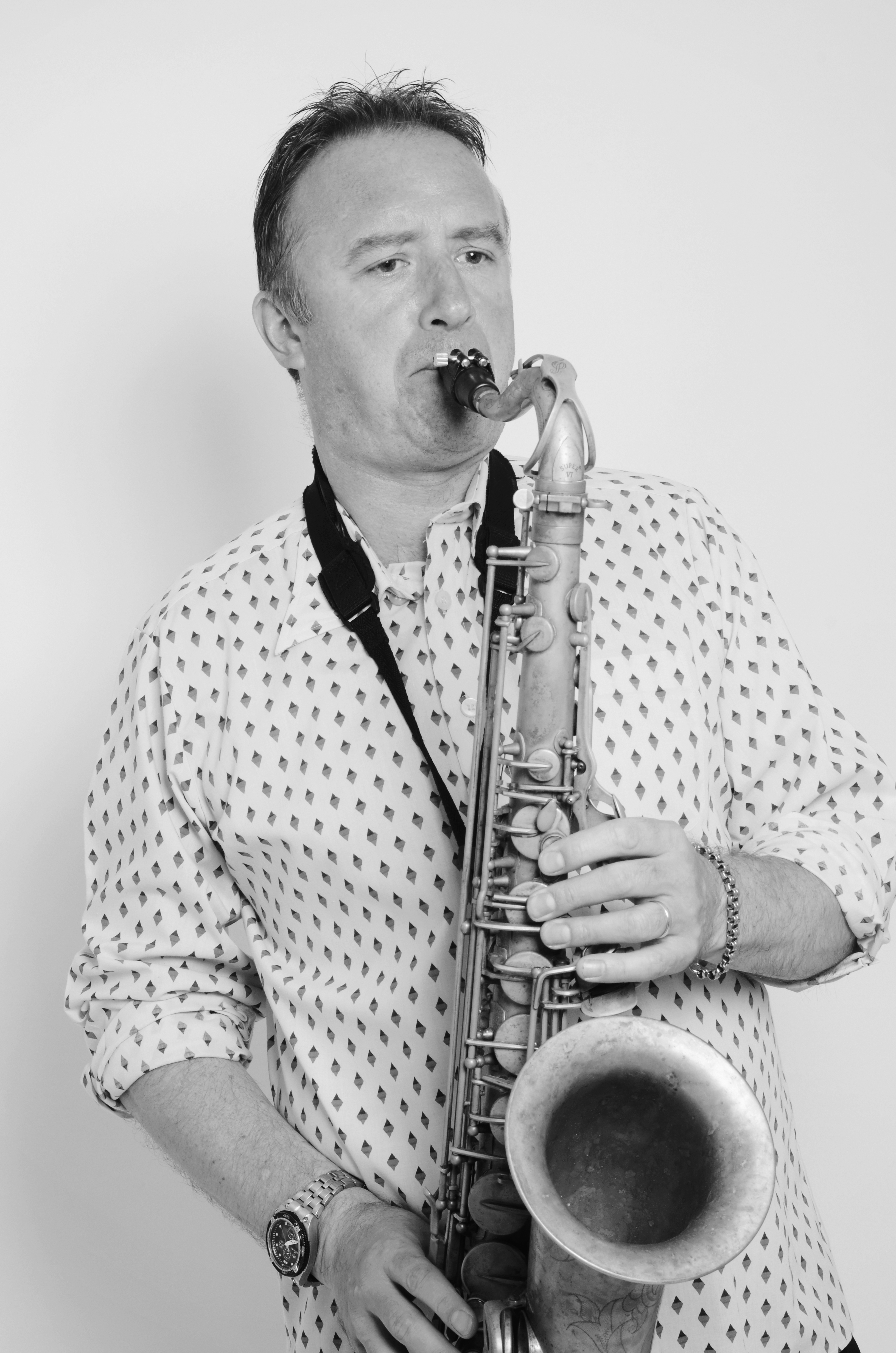 Black and white studio portrait of Tim Fulker playing tenor saxophone